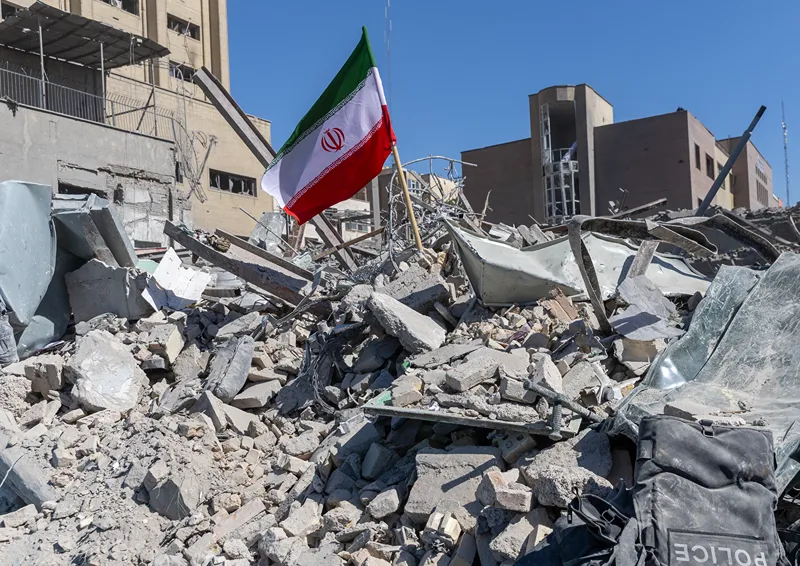 דגל איראן על רקע אתר שהותקף בטהראן, 3 במרץ 2026