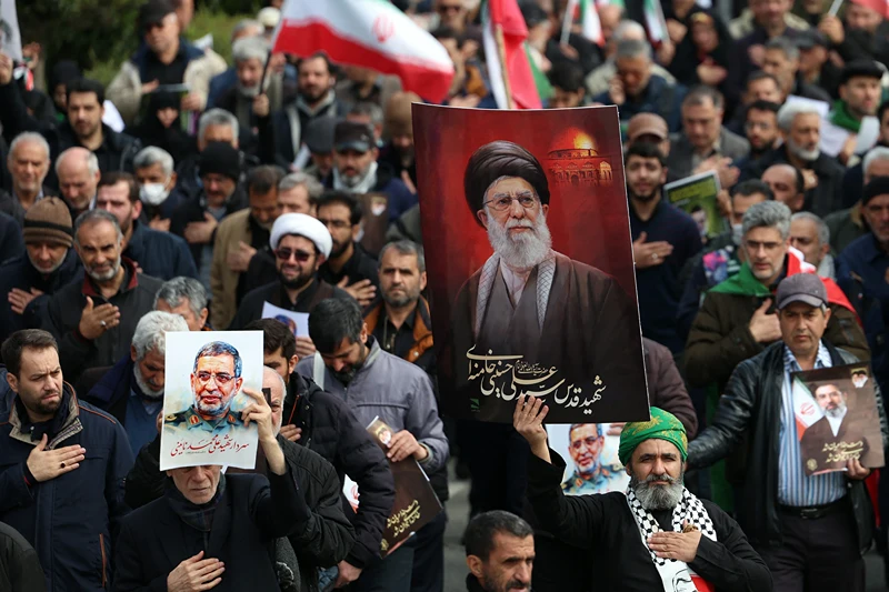 איראנים מחזיקים תמונה של המנהיג העליון שחוסל, עלי ח'מינאי, במהלך הלוויתו של דובר משמרות המהפכה, עלי מוחמד נאיני, שחוסל על ידי ישראל, 21 במרץ 2026