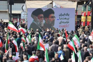 תומכי המשטר נושאים שלט של המנהיג העליון של איראן, מוג'תבא ח'מינאי, והמנהיג העליון לשעבר, עלי ח'מינאי, במהלך טקס ההלוויה של עלי לריג'אני בטהראן, 18 במרץ 2026